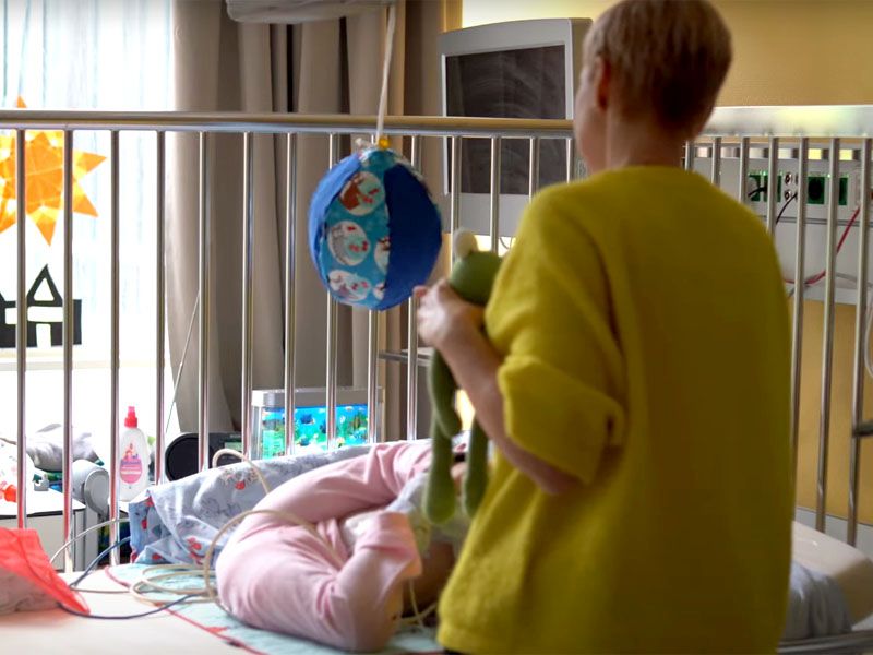 Erzieherin am Bett eines kleinen Patienten im Olgahospital