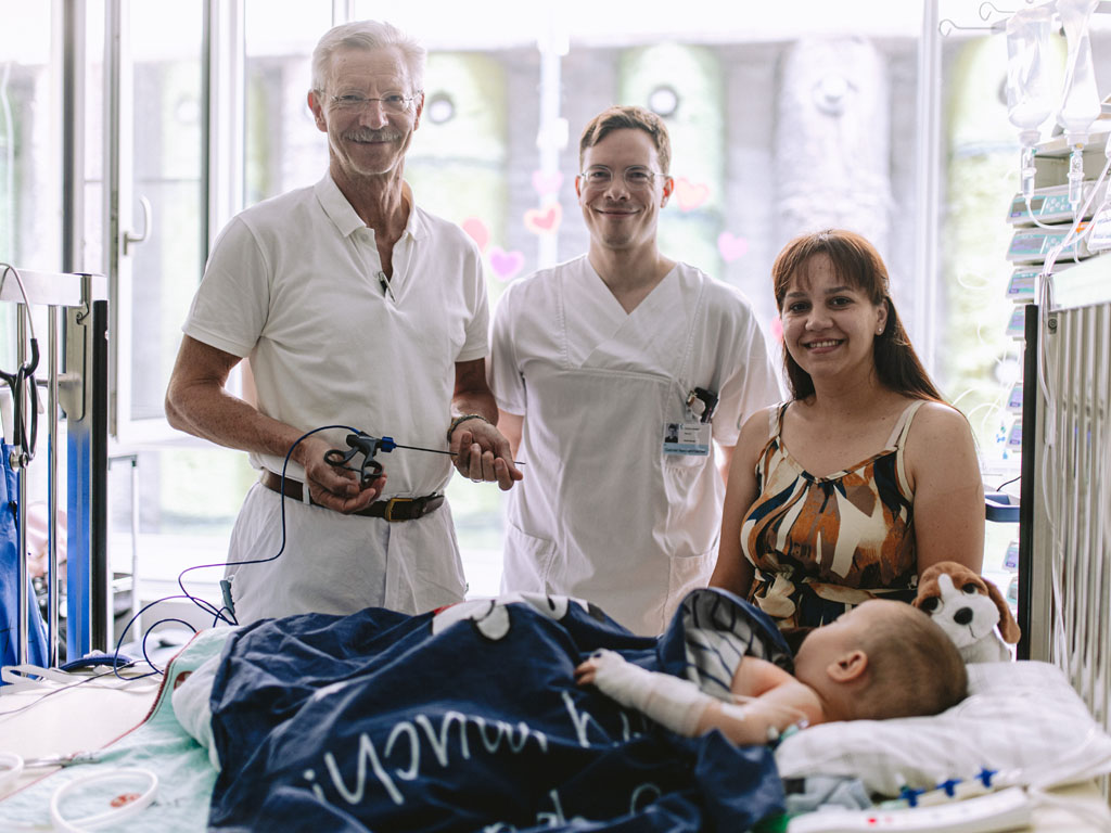 2 Ärzte und eine Mutter stehen am Patientenbett eines kleinen Jungen